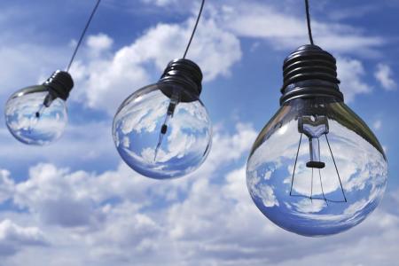 Three light bulbs hanging against a blue sky with clouds